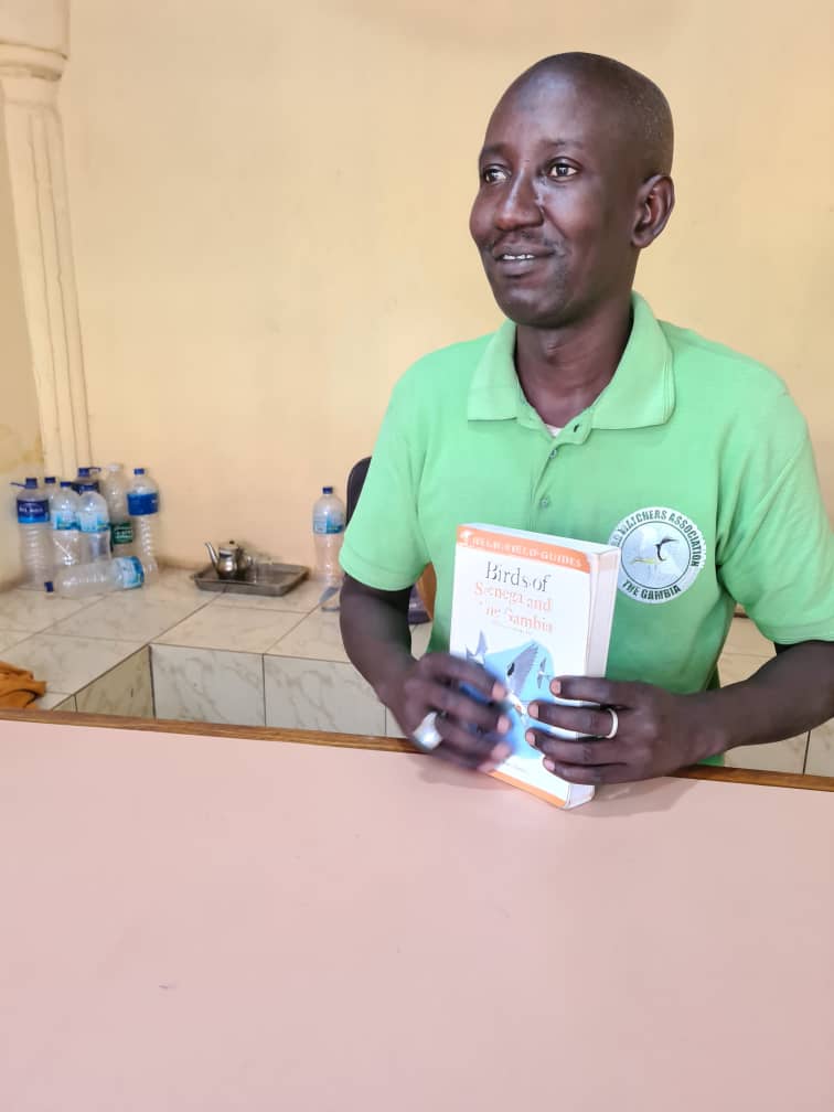 Assan standing at the Senegambia office desk